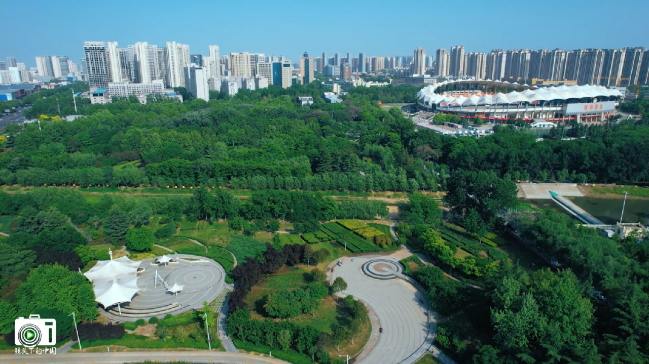 郑州经开区滨河公园内绿树成荫芳草青青鲜花盛开鸟语花香游人如织