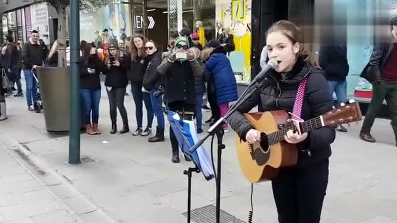 街頭女孩手握吉他邊奏邊唱,一首好聽的英文歌曲贏得了觀眾的打賞