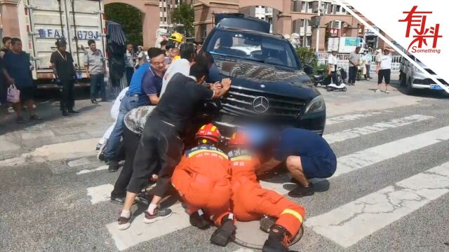 女子骑电动车连人带车被困越野车车底 消防员连手热心市民抬车营救