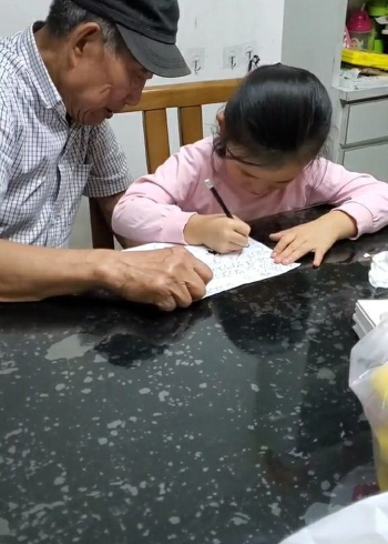 爷爷教孙女写字,孙女写烦了不想写了,爷爷扫帚都用上了