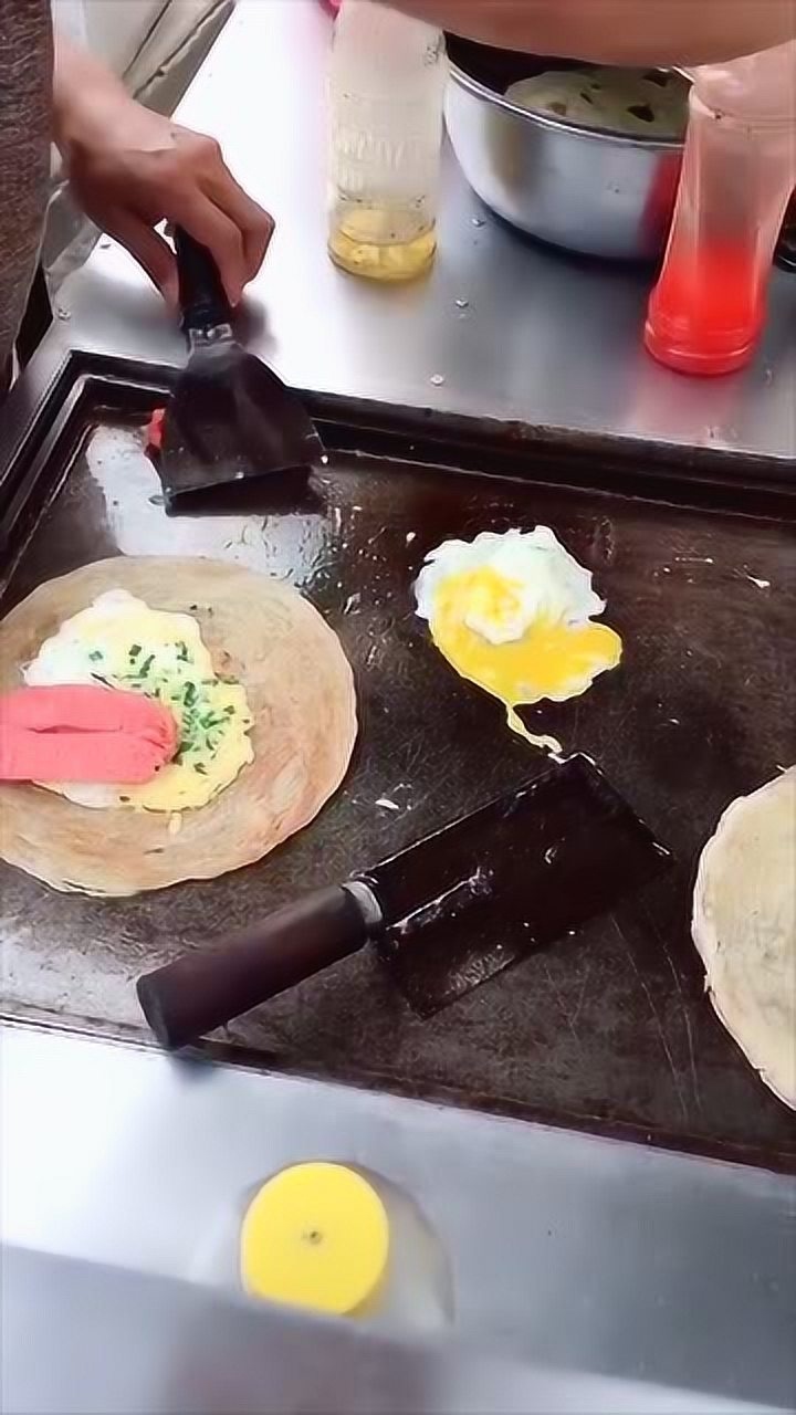 农村小伙街头摆摊卖手抓饼热狗鸡蛋加少许葱花5元一个很划算